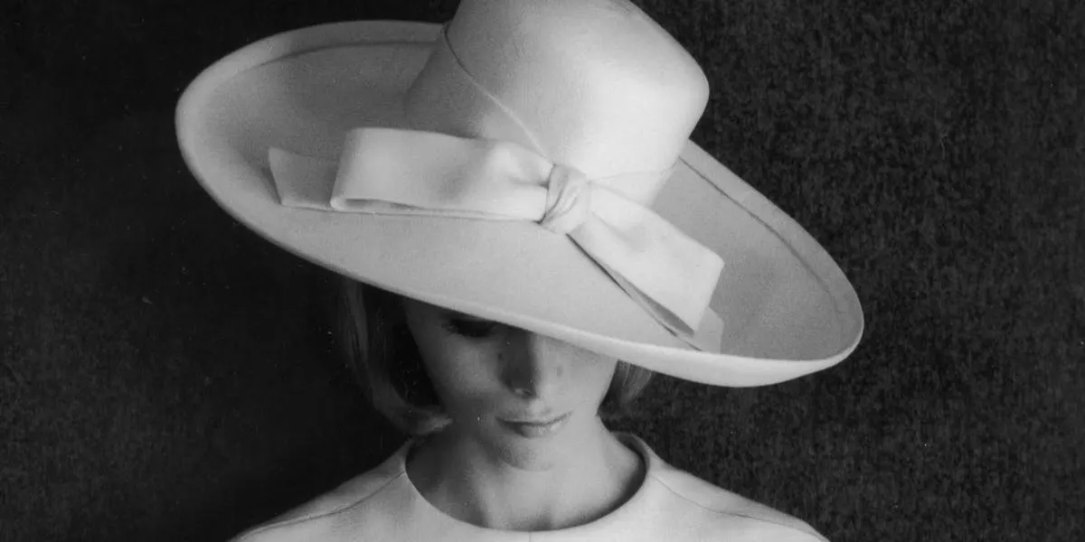 En tvådelad klänning i vitt linne, designad av Yves Saint Laurent. Klädseln bärs med en hatt och kommer från hans "Boutique Collection". Foto © Barry Lategan/Getty Images