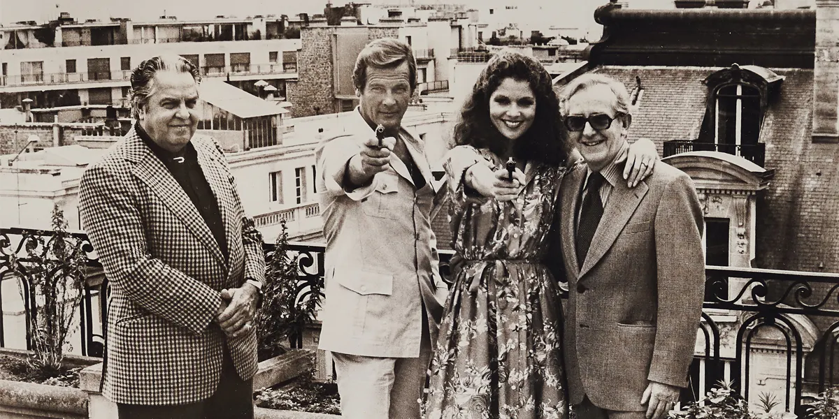 A black-and-white press still of Lewis Gilbert with Cubby Broccoli, Roger Moore and Lois Chiles posing on a Parisian rooftop in 1978. Part of ‘Moonraker’ (1979) lot with a director’s copy of the script. Photo © Bellmans