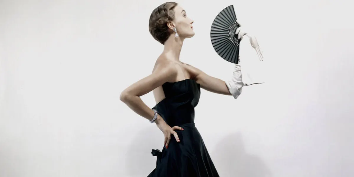 Modèle de profil portant une robe de soirée Christian Dior en satin noir, un long gant blanc tenant un éventail (détail), image © Erwin Blumenfeld / Condé Nast via Getty Images