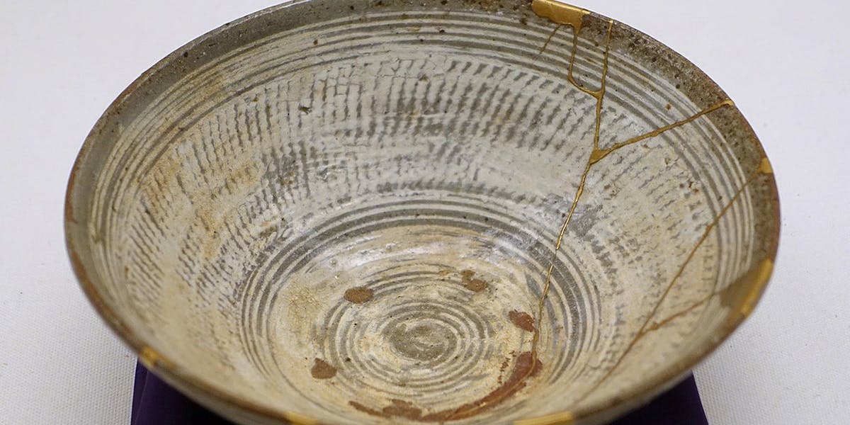 Lavori di riparazione (a destra) su una ciotola da tè tipo hakeme in ceramica Mishima con lacca dorata kintsugi, XVI secolo, in mostra al Museo Etnologico di Berlino, Germania. Foto di Daderot, CC0 (dettaglio)