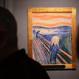 Spettatori che osservano "L'Urlo" di Edvard Munch, esposto al Museum of Modern Art (MOMA) di Manhattan per una mostra di sei mesi il 25 ottobre 2012 a New York City. Il motivo più famoso dell'artista norvegese, e uno dei dipinti più iconici del mondo, è stato venduto per quasi 120 milioni di dollari dalla casa d'aste Sotheby's a maggio ed è l'unica delle quattro versioni in mano a privati. Foto: Spencer Platt via Getty Images