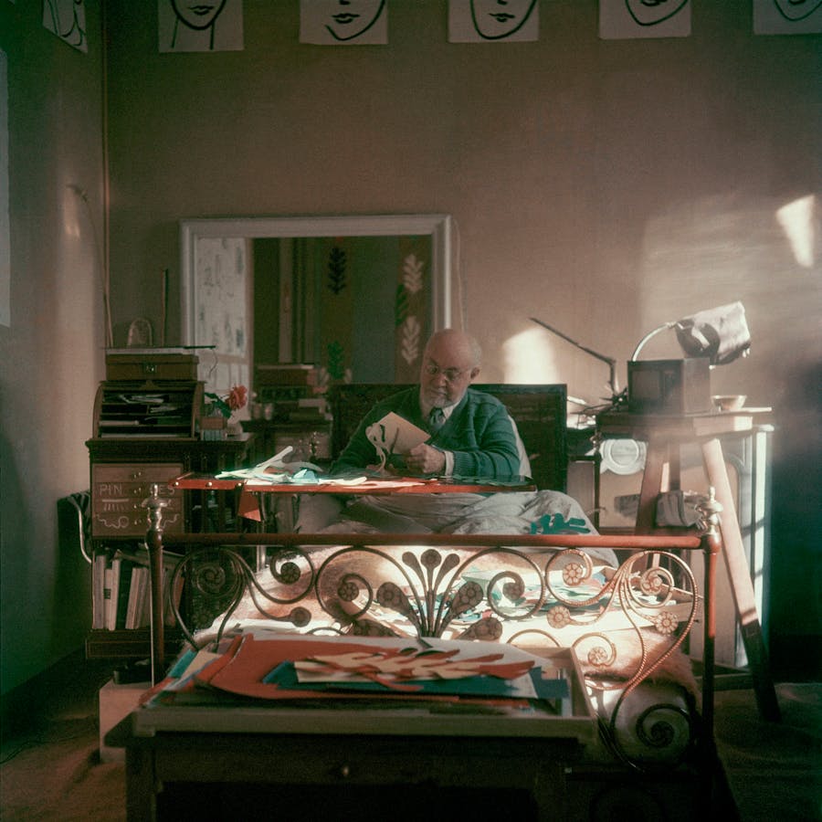 L'artista Henri Matisse, seduto a letto, lavora su disegni di chiese. Indossa un maglione verde sopra una camicia bianca e una cravatta nera. Foto Clifford Coffin/Condé Nast via Getty Images