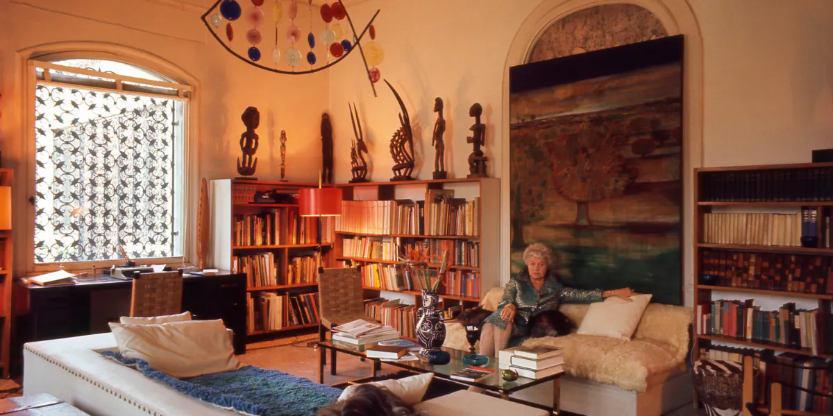 Peggy Guggenheim in biblioteca, Palazzo Venier dei Leoni, Venezia, 1975. Sul retro della libreria, da sinistra a destra: gancio di sospensione, artista latmul occidentale non registrato, inizio XIX - inizio XX secolo, Papua Nuova Guinea; figura maschile, artista non registrato, inizio XX secolo, Papua Nuova Guinea. Sul retro della libreria di destra: copricapo femminile Ci Wara, probabilmente prima metà del XX secolo, artista Bamana non registrato, regione di Segou, Mali; copricapo maschile Ci Wara, probabilmente prima metà del XX secolo, artista Bamana non registrato, regione di Segou, Mali; figura maschile (pombia), probabilmente metà del XX secolo, artista Senufo non registrato, Costa d'Avorio; figura maschile seduta, probabilmente prima metà del XX secolo, artista Dogon non registrato, regione di N'duleri, Mali. Fondazione Solomon R. Guggenheim. Foto Ray Wilson. Acquisto Collezione Peggy Guggenheim, 2007 via Collezione Peggy Guggenheim (dettaglio)