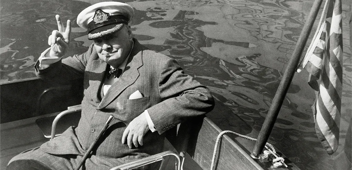 Winston Churchill macht in einem Boot das Victory-Zeichen. Der ehemalige britische Premierminister Winston Churchill macht das Victory-Zeichen während der Fahrt in einem Motorboot im Hafen von Safi, Marokko. Er ist auf dem Weg zur Yacht Christina von Aristoteles Onassis. Foto: Getty Images (Detail)