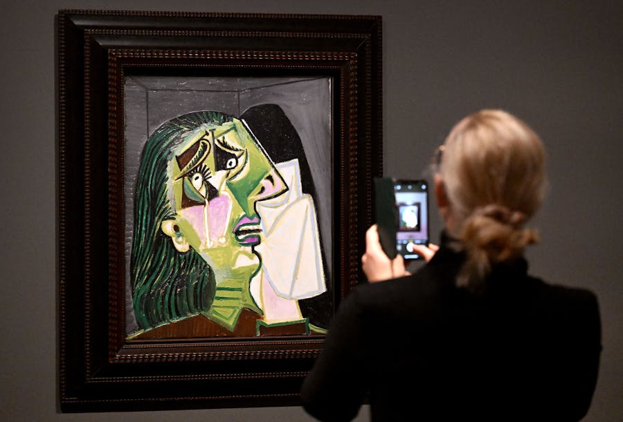 A person takes a photo of a painting titled "Weeping Woman" by Pablo Picasso at an exhibition of more than 80 artworks by him at the National Gallery of Victoria in Melbourne on June 9, 2022. (Photo by WILLIAM WEST/AFP via Getty Images)