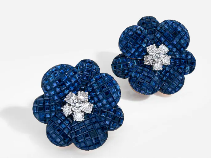 Paire de clips en or jaune, les pétales épanouis et bombés, ornés de saphirs calibrés en serti mystérieux, le cur serti de diamants sur platine, par Van Cleef &amp; Arpels