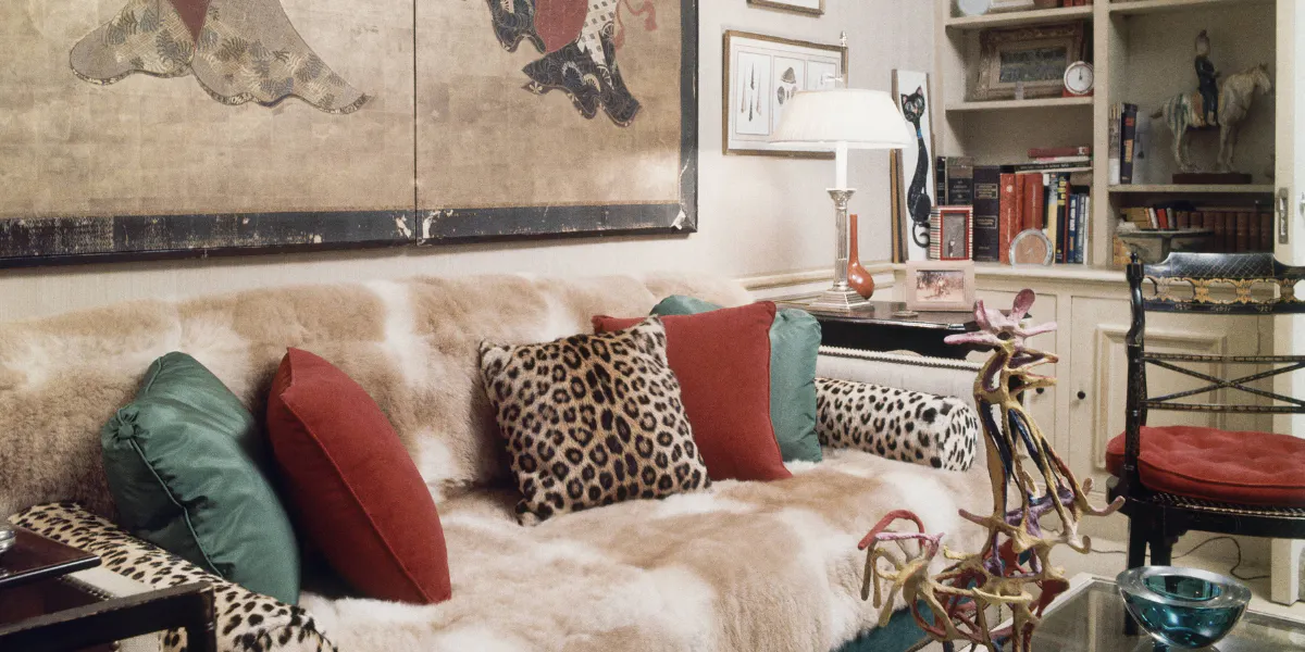 Detaljbild på vardagsrum med vikunjasoffan och leopardmönstrade kuddar. På bordet står en skulptur i papier mache föreställande en tupp. Foto: Horst P. Horst/Conde Nast via Getty Images