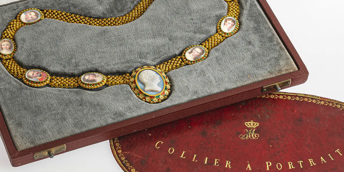 Collier mit Chalcedon-Gemme und acht Medaillons mit Miniaturporträts, München, um 1818, Gold en-deux-couleurs 750/-, gestempelt, Chalcedon-Gemme, Glas, rotes und grünes Transluzidemaille, Emaillemalerei, Aquarell und Deckfarben auf Elfenbein, L. ca. 60 cm, Gewicht 98,42 g cm, Etui (20. Jh.), dazu: Klappe des originalen Etuis mit Monogramm, Bezeichnung und Nummerierung. Foto © Neumeister (Detail)