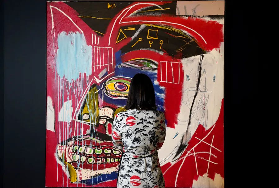 Une femme regarde « In This Case » de Jean-Michel Basquiat lors d'une avant-première presse le 3 mai 2021 pour les ventes du soir des XXe et XXI siècles de Christie's à New York. Photo de TIMOTHY A. CLARY/AFP via Getty Images