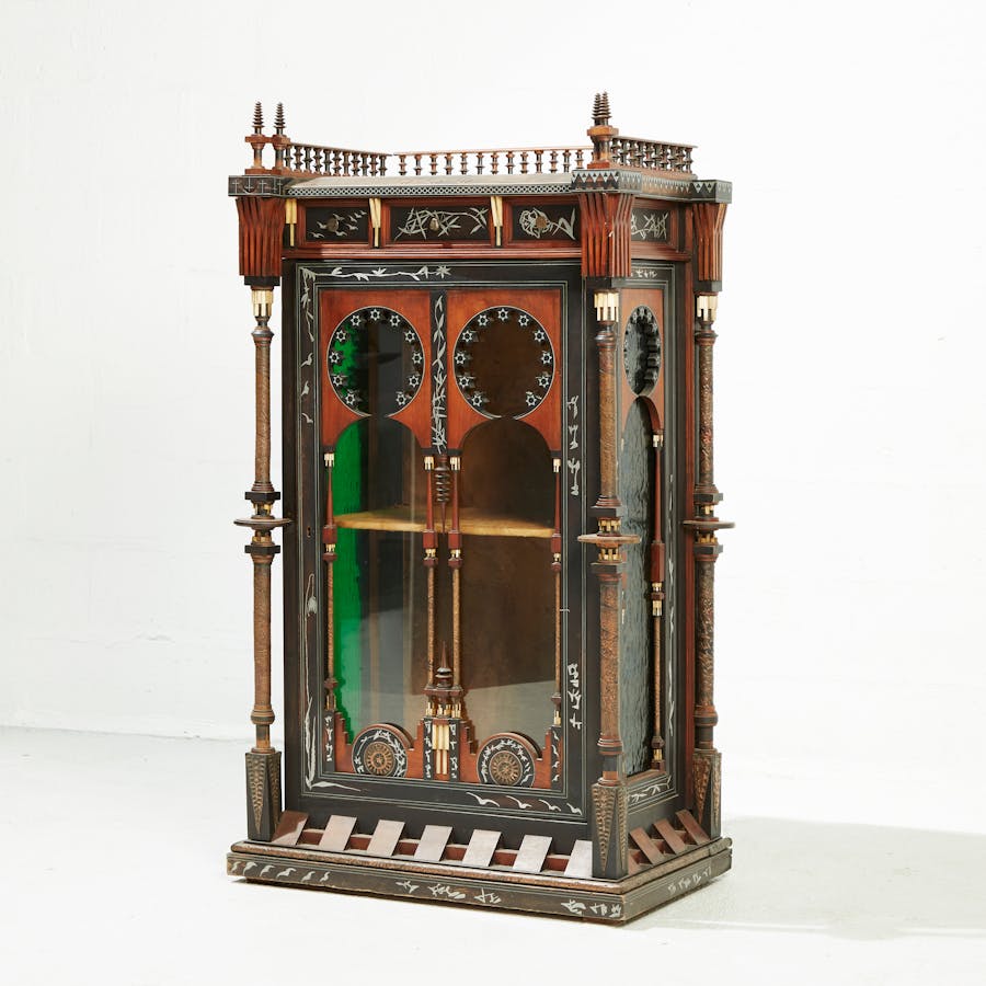 CARLO BUGATTI (1856-1940), Vitrine orientaliste, circa 1900, structure en bois teinté, incrustation d'éléments végétaux, oiseaux et calligraphies en acier, colonnettes détachées torsadées de cuivre repoussé, ornements en bois et ivoire, prises du tiroir central formée d'un insecte stylisé en bronze patiné, H 133,5 x L 73,5 x P 44,5 cm. Image © Art Paris Research