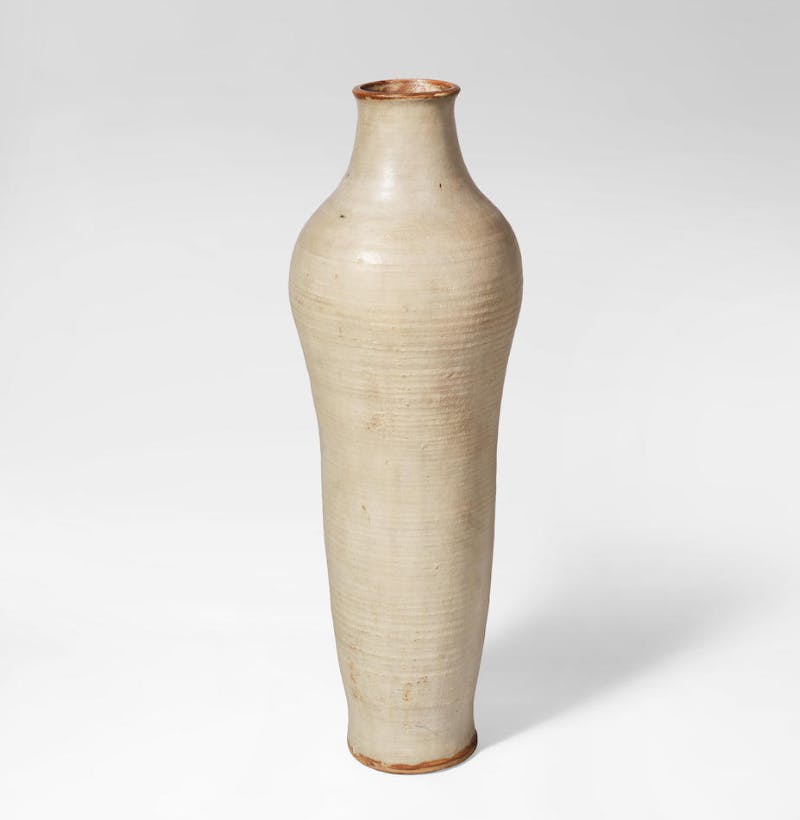 William Staite Murray, A Large Exhibition Vase, circa 1955. Stoneware, of elongated baluster form with a gently ridged surface, in a pale cream and grey glaze, with some mottled brown streaks. Photo © Bonhams 