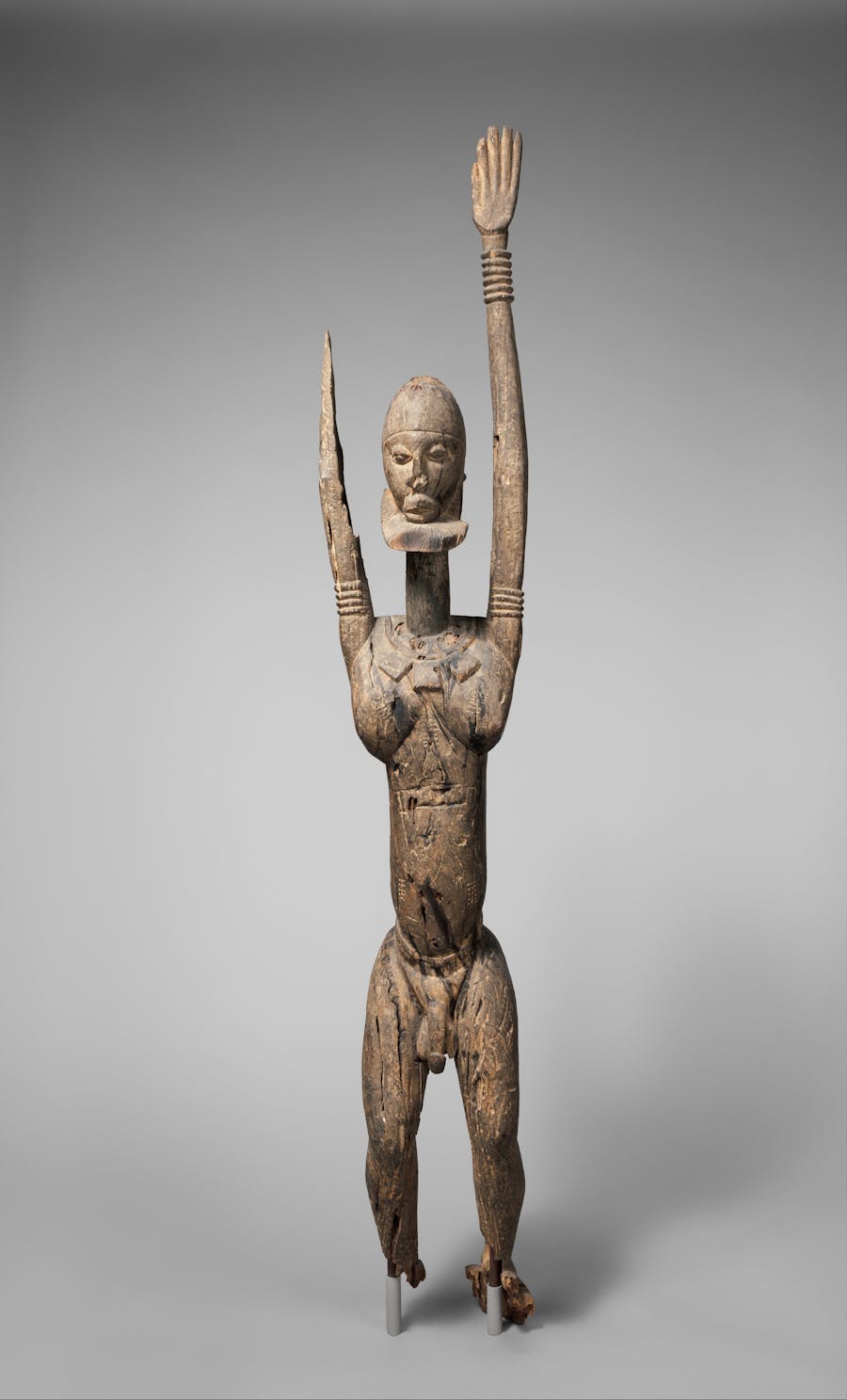 Dogon male figure with raised arms, 14th–17th century, Mali, wood and patina. Public domain image