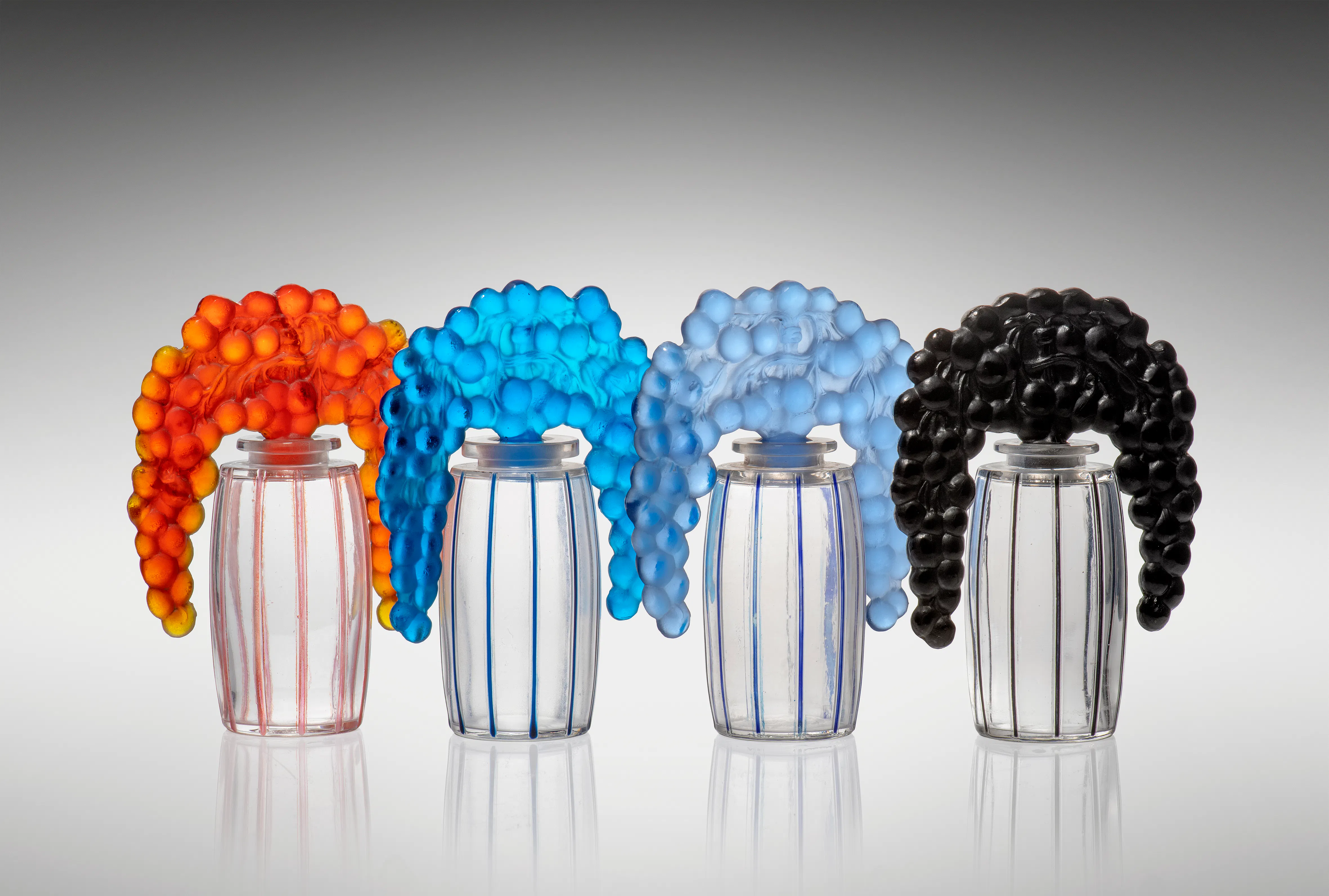 Bouchon Cassis Scent Bottles, designed 1920, clear, black, blue, orange and black enamelled, moulded R. LALIQUE, 11cm high. Photo © Lyon & Turnbull
