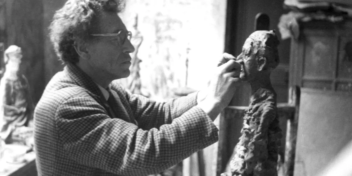 Alberto Giacometti realizza una scultura che raffigura la moglie Annette. Foto © Successione Alberto Giacometti (Fondation Giacometti, Parigi + ADAGP, Parigi) 2019. FAAG Paris / CC BY-SA 4.0 via Wikimedia Commons (dettaglio)
