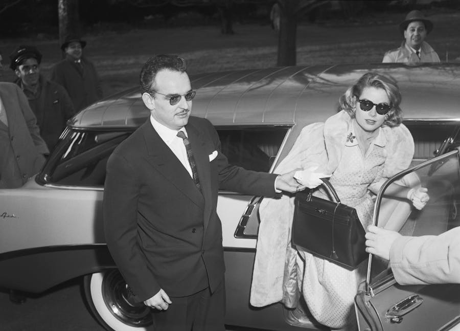 Prince Rainier III of Monaco helping his fiancee Grace Kelly out of a car. Kelly holds the style of Hermès handbag that was named after her. Image Bettmann/Contributor via Getty Images