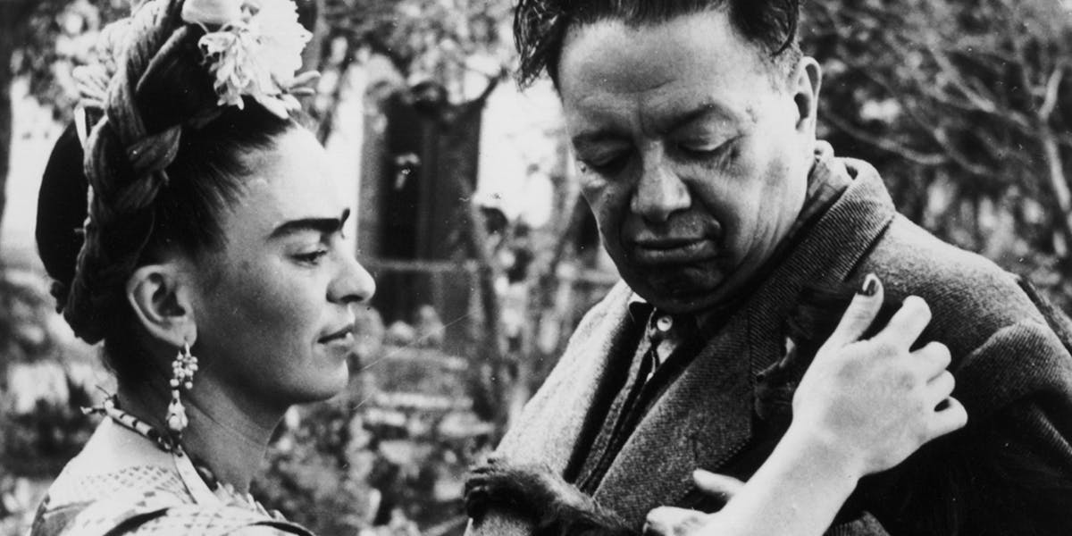 Circa 1945: Mexican artist Frida Kahlo (1907-1954) strokes a monkey, possibly Fulang-Chang, clinging to her husband's jacket, Mexican artist Diego Rivera (1886-1957). Photo by Wallace Marly / Hulton Archive / Getty Images