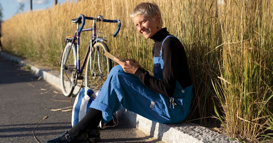 A woman reading a book next to her bike and wheat field