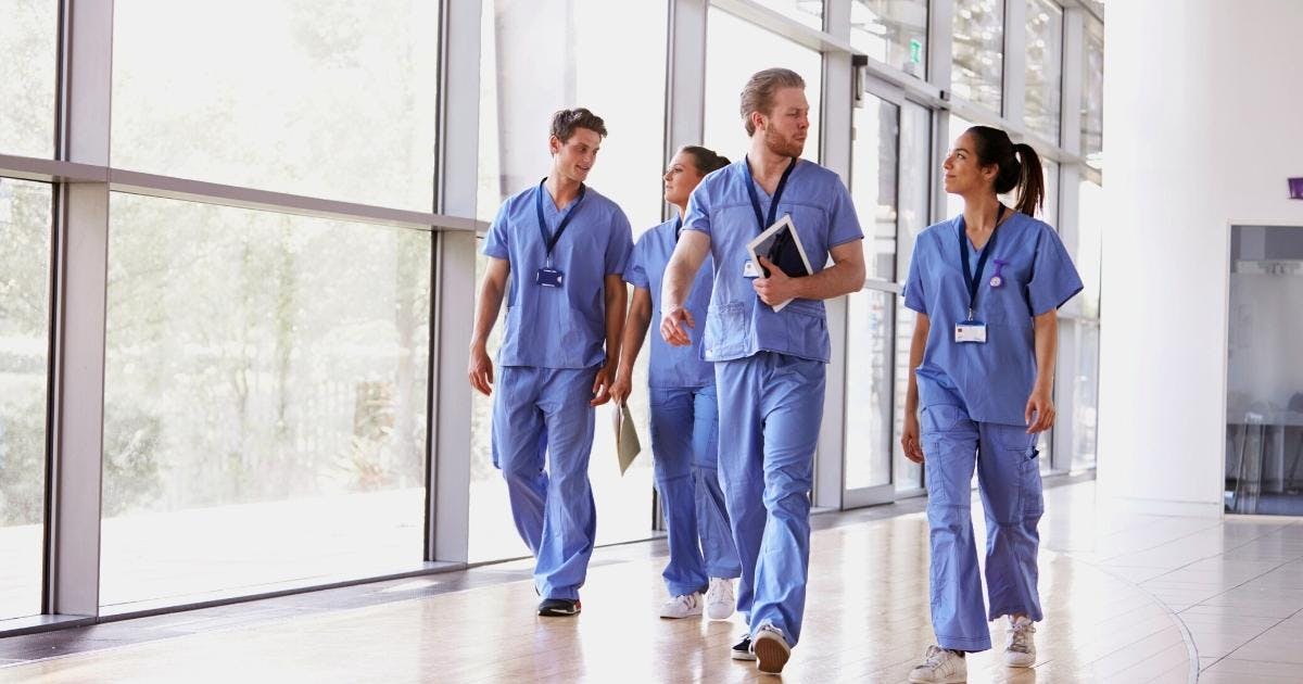 Joukko hoitajia kävelee sairaalan tai terveyskeskuksen käytävällä.