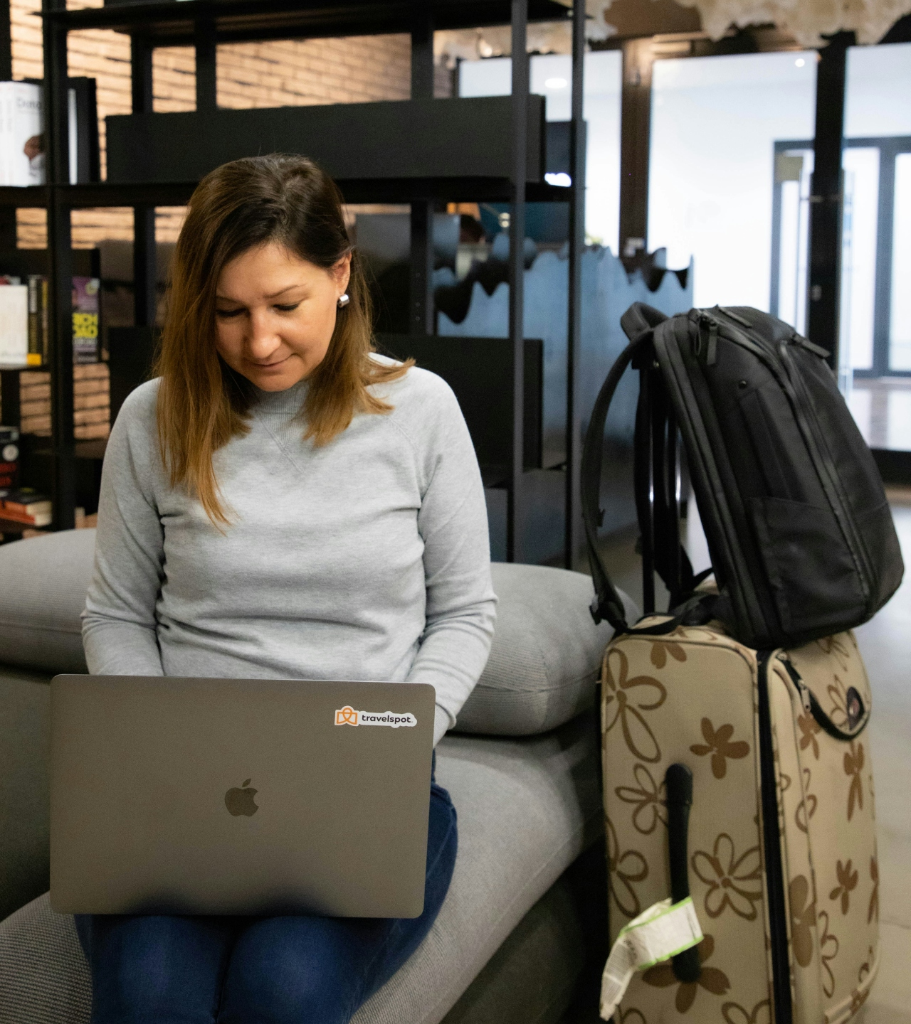 Woman with a suitcase working on a laptop