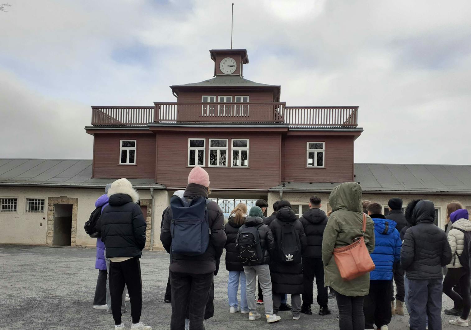 People standing with their backs turned in front of the entrance to Buchenwald