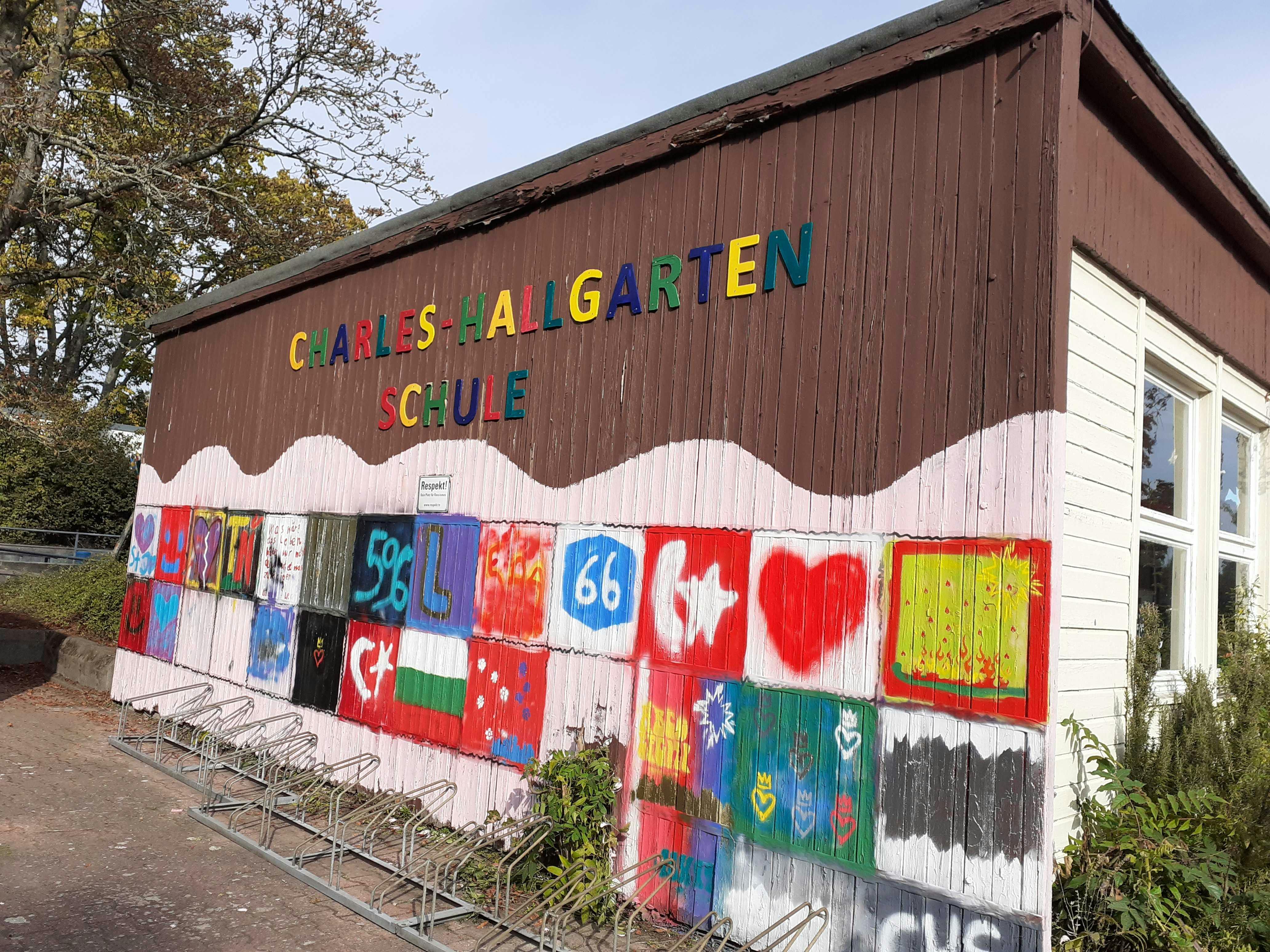 On the photo one can see a wall of the Charles Hallgarten School with many small graffiti pictures on it. Some show hearts or stars, for example.