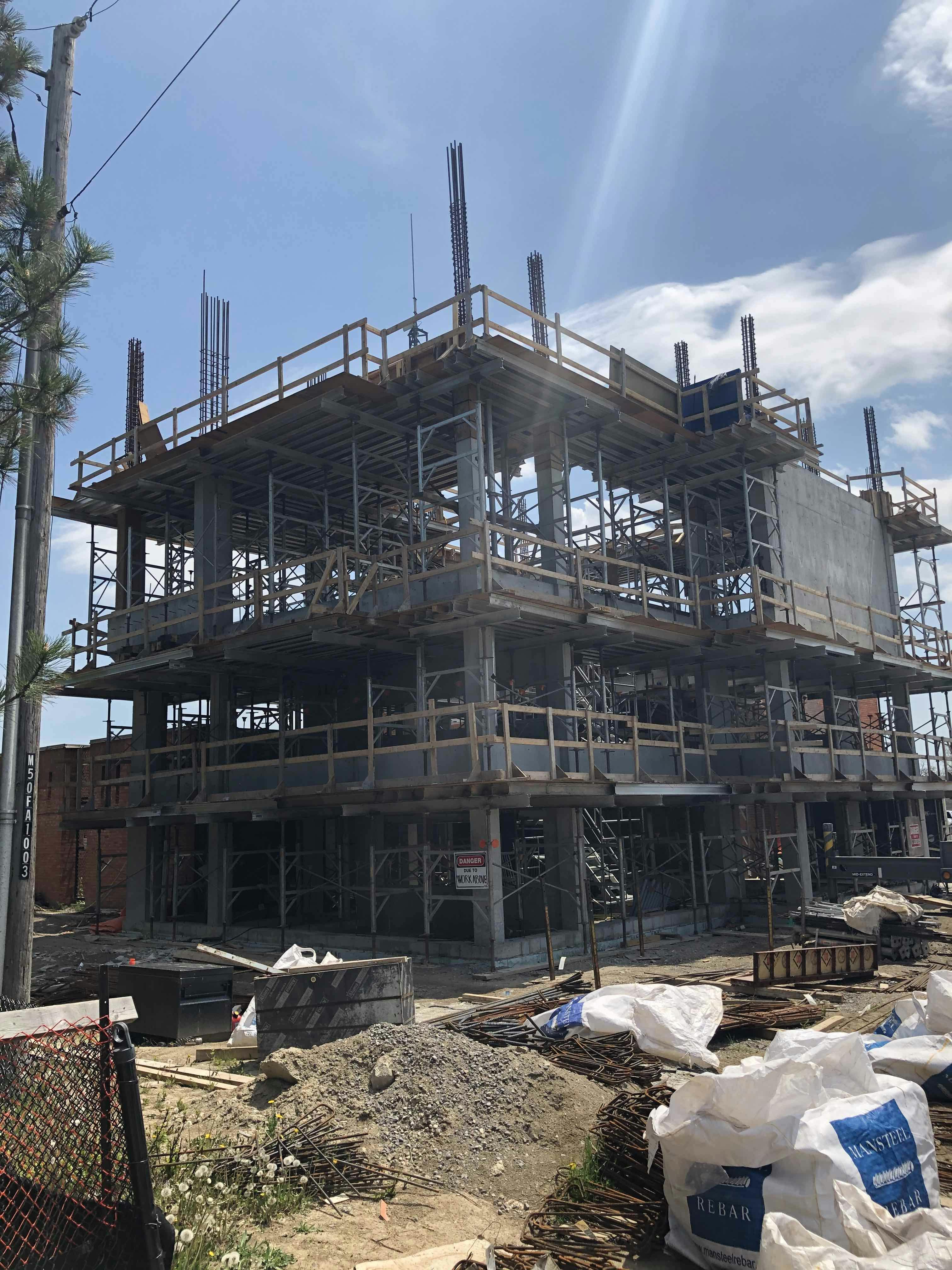 Multi-story building under construction with scaffolding and construction materials on the ground