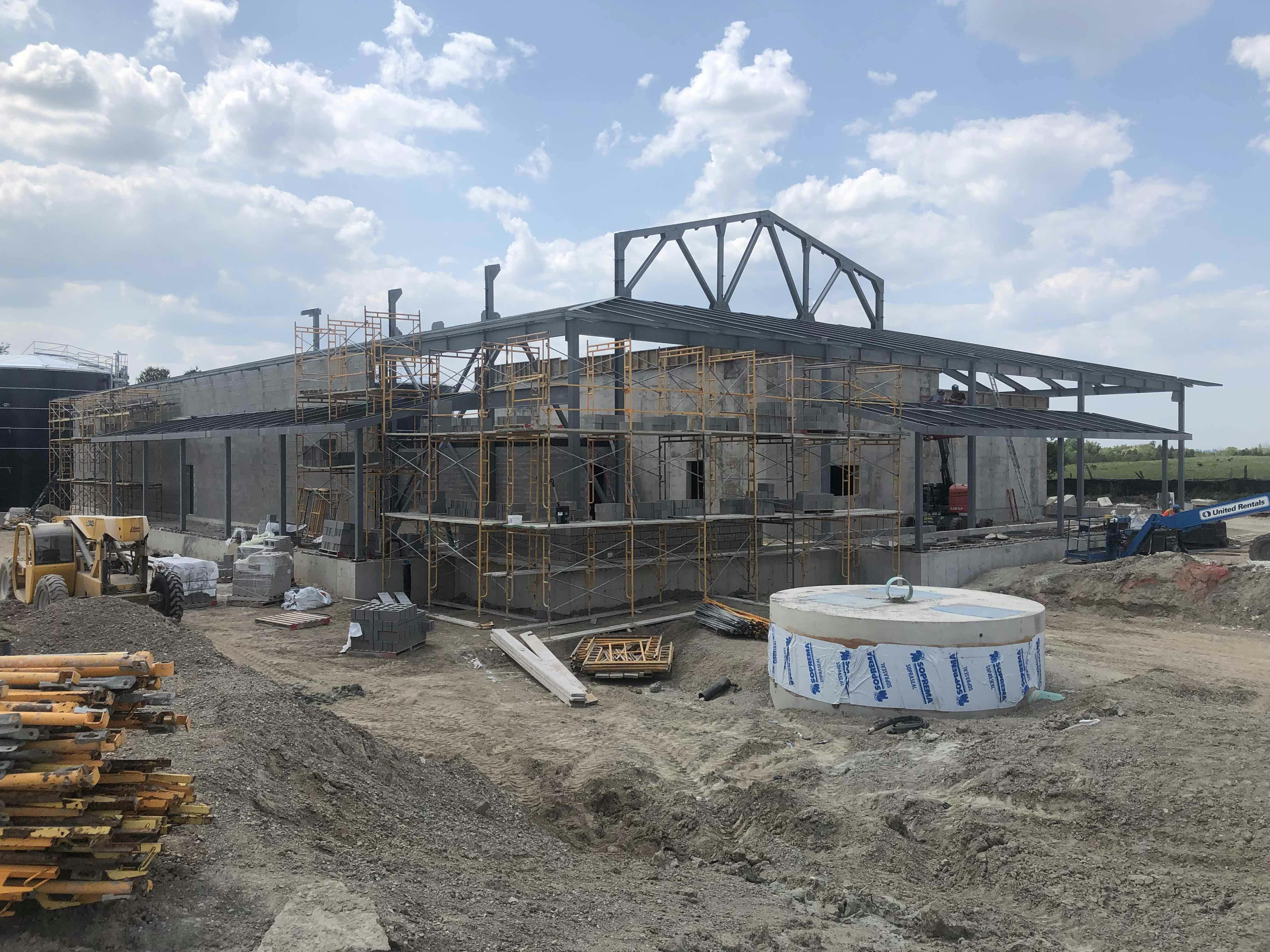 Construction site with a partially built structure, scaffolding, construction materials, and equipment on the ground