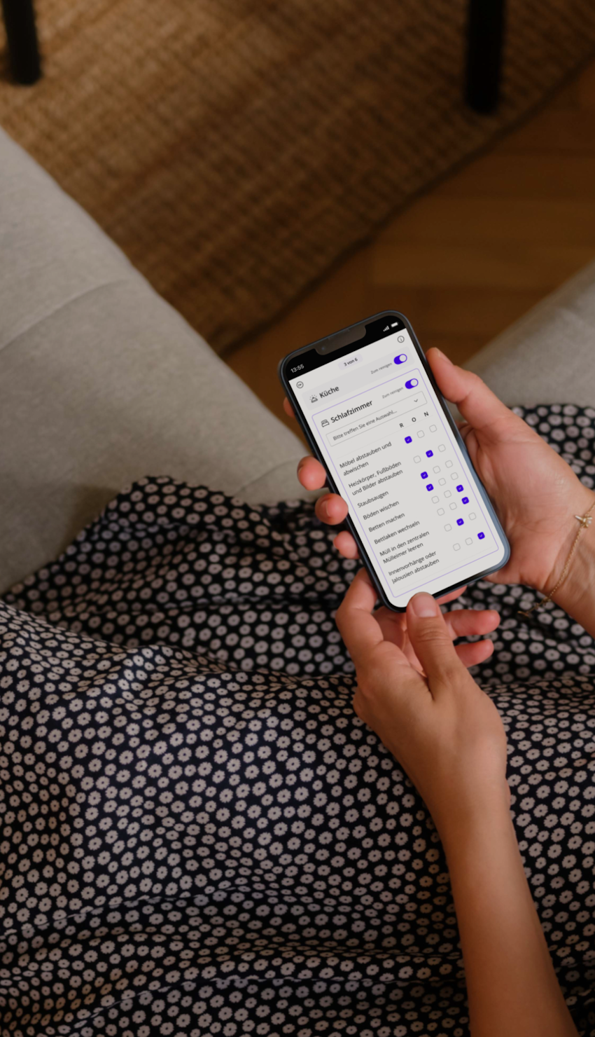 Person entspannt auf dem Sofa, erkundet die Batmaid-App mit geöffneter Checklistenfunktion.