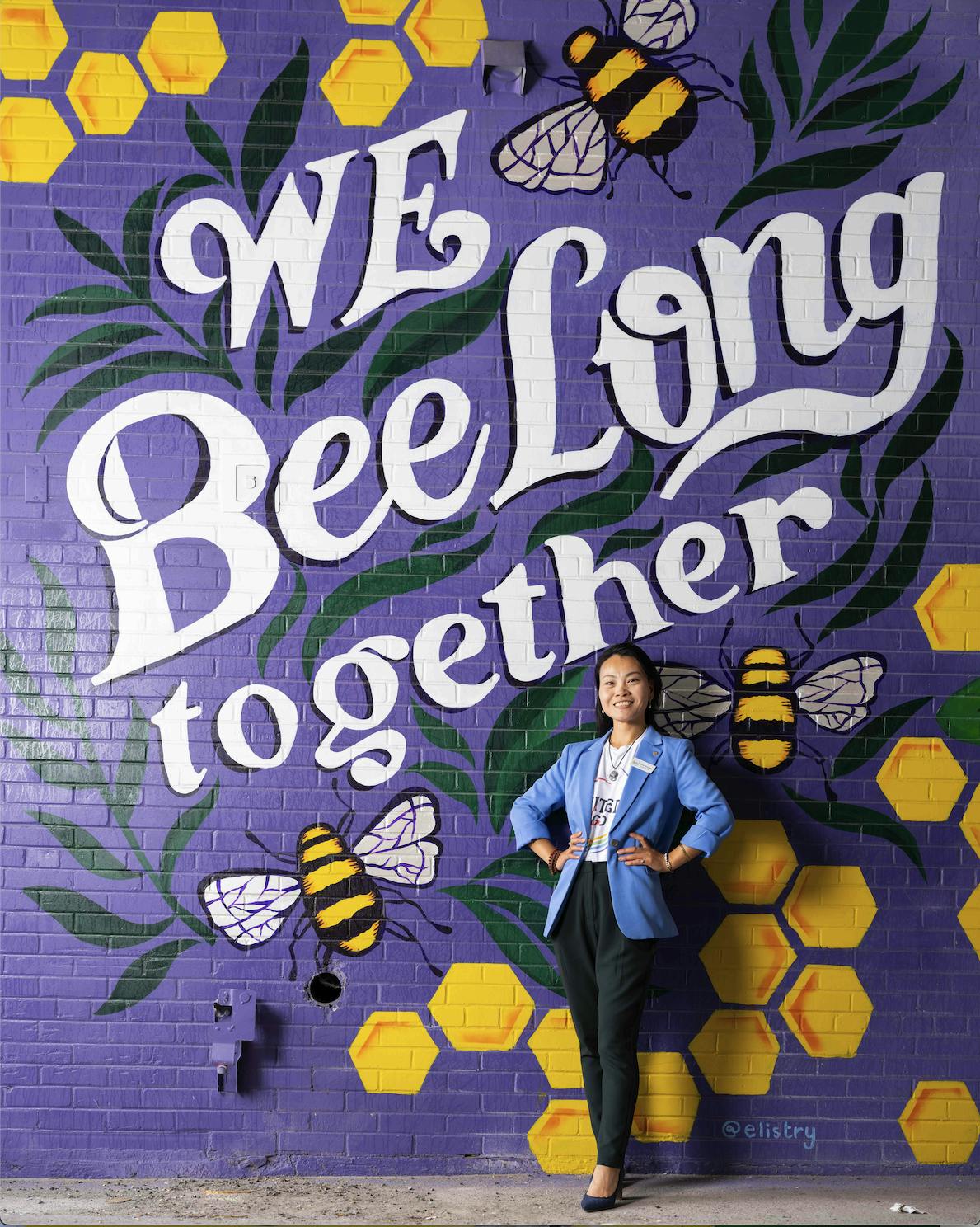Gina Anayana of United We Go standing in front of a mural painted during Bay City's City of Mural Festival