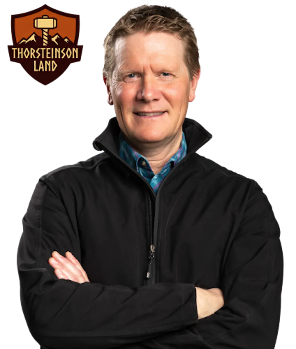 Shield badge with a farm scene including fields and a structure, labeled “Thorsteinson Land,” in brown and gold tones beside a photo of Gary Thorsteinson with his arms crossed 