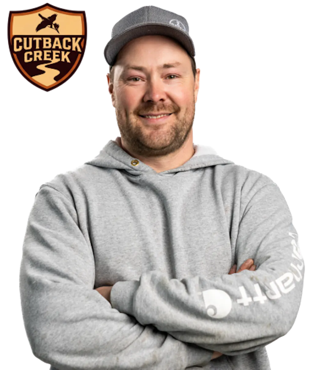 Shield-shaped logo in tan and dark brown with the words 'Cutback Creek' in bold lettering, featuring a flying bird silhouette above and a winding creek path below beside a photo of William Brown with his arms crossed.