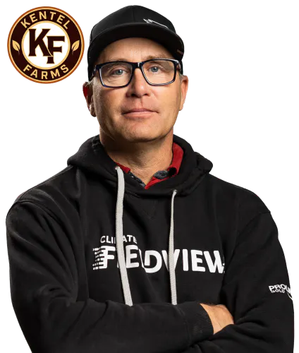 Circular badge with the letters “KF” in the center and “Kentel Farms” around the edge, in gold and dark brown beside a photo of Derek Kentel with his arms crossed