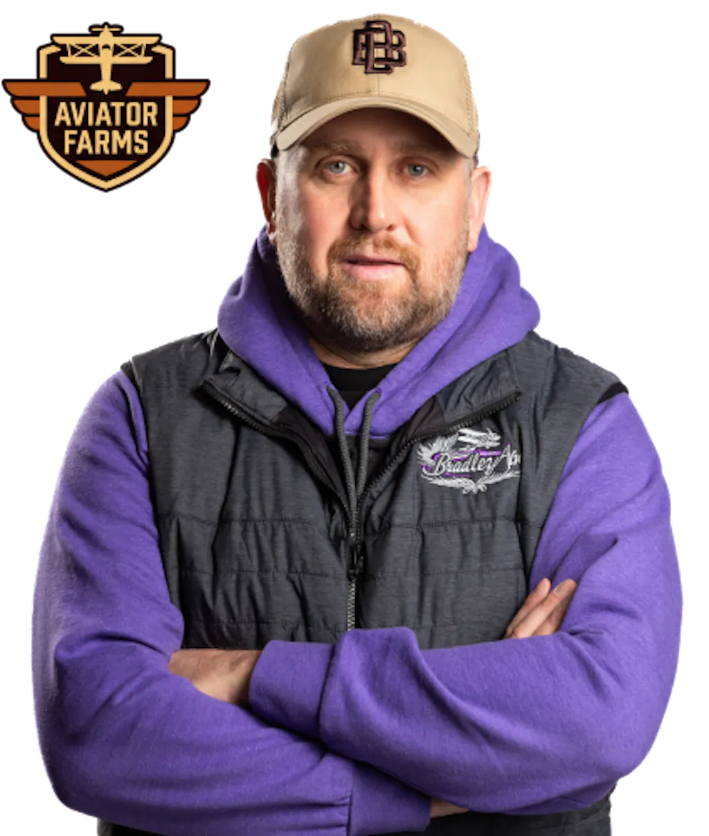Shield-shaped badge featuring a small airplane above stylized wings, with the text “Aviator Farms” in tan and brown tones beside a photo of Garth George with his arms crossed