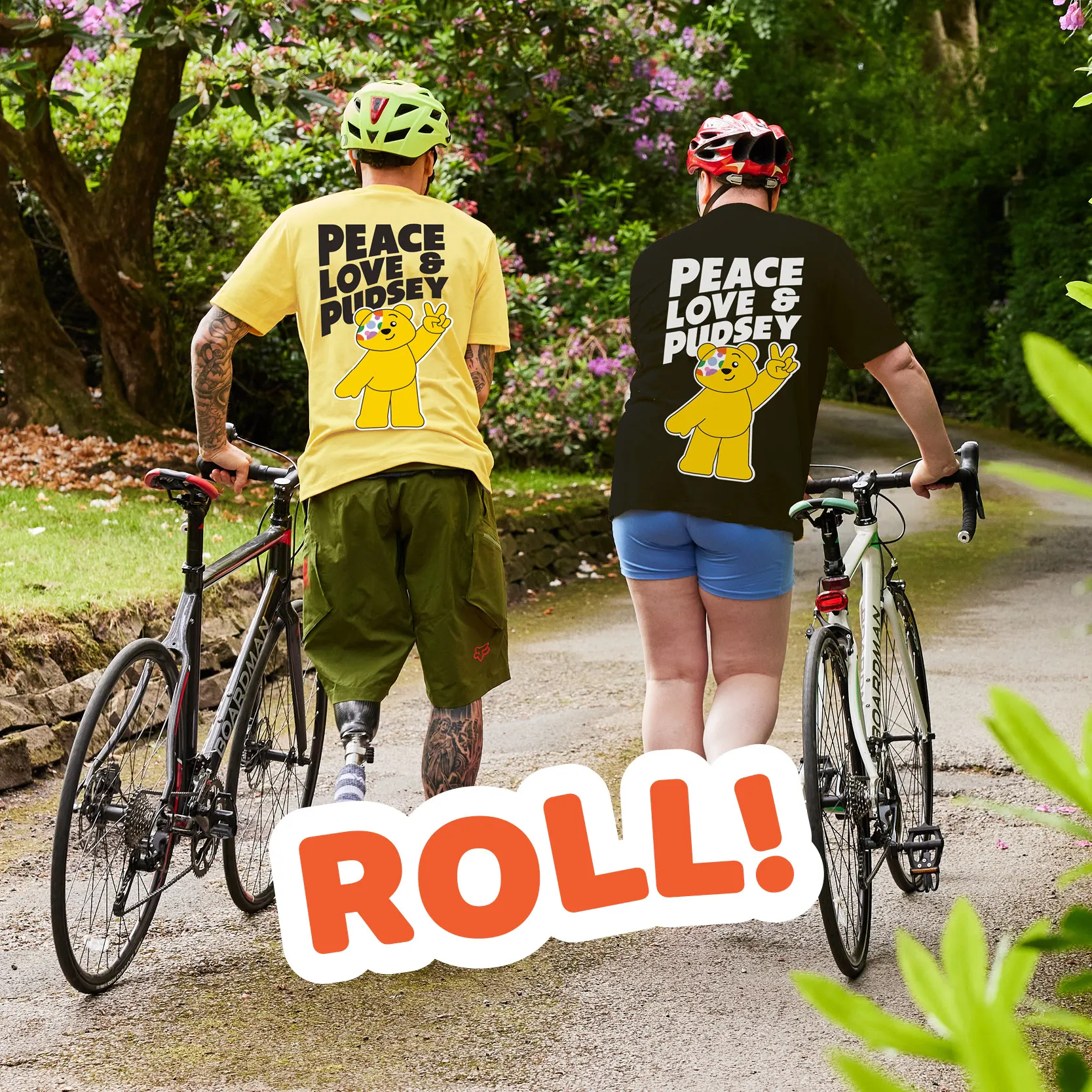 Two people walking with their bikes whilst wearing Pudsey t-shirts.