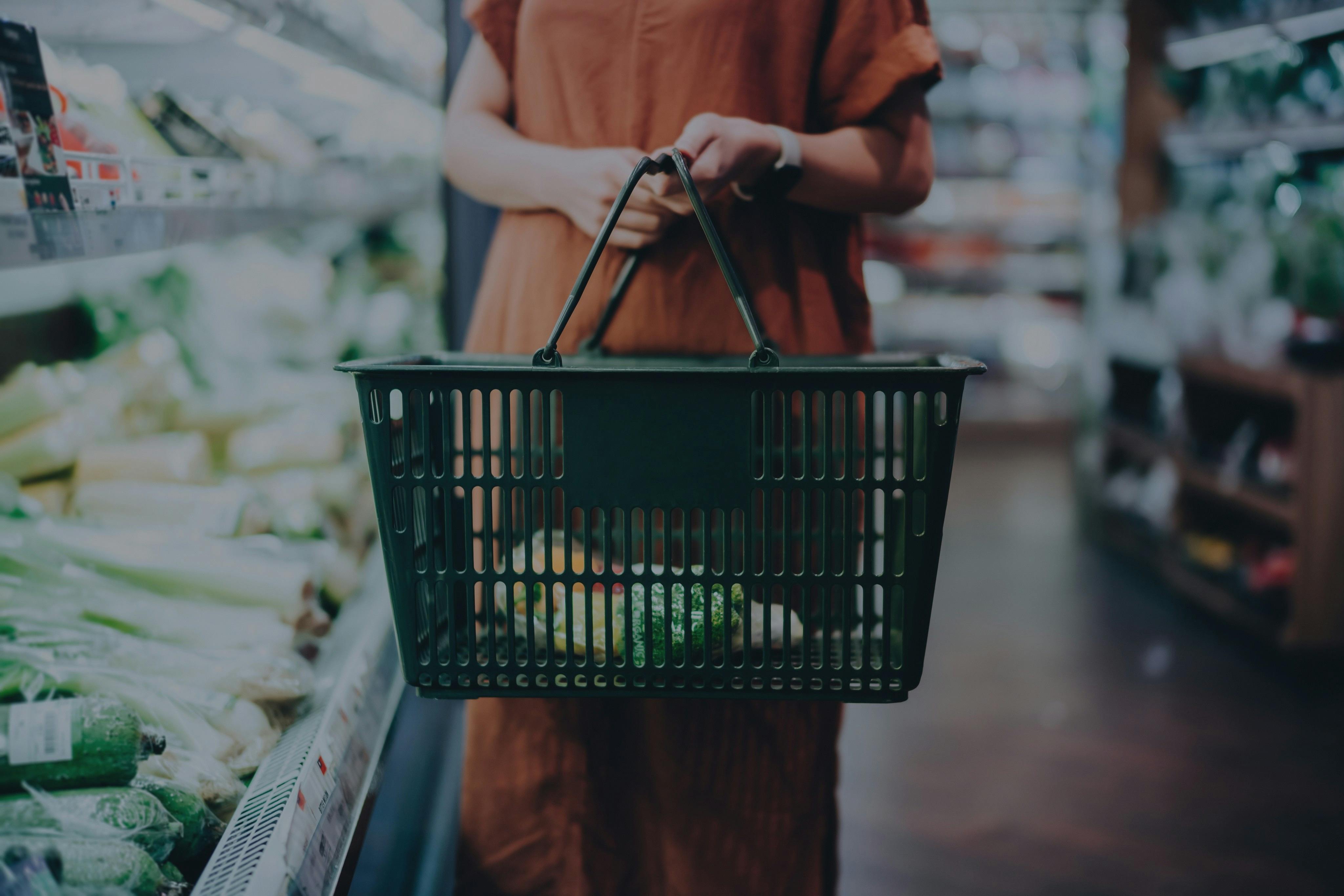 shopper with basket in grocery store aisle