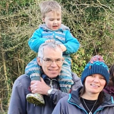 Photo of Sarah and her dad outside, with a young child sitting on her dad's shoulders.