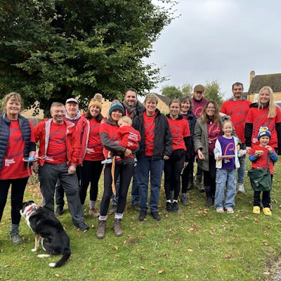 Sarah smiling to the camera with her team, all wearing their Blood Cancer UK t-shirts in a residential neighbourhood.