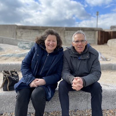 Photo of Sarah's parents sitting together on a bench outside.