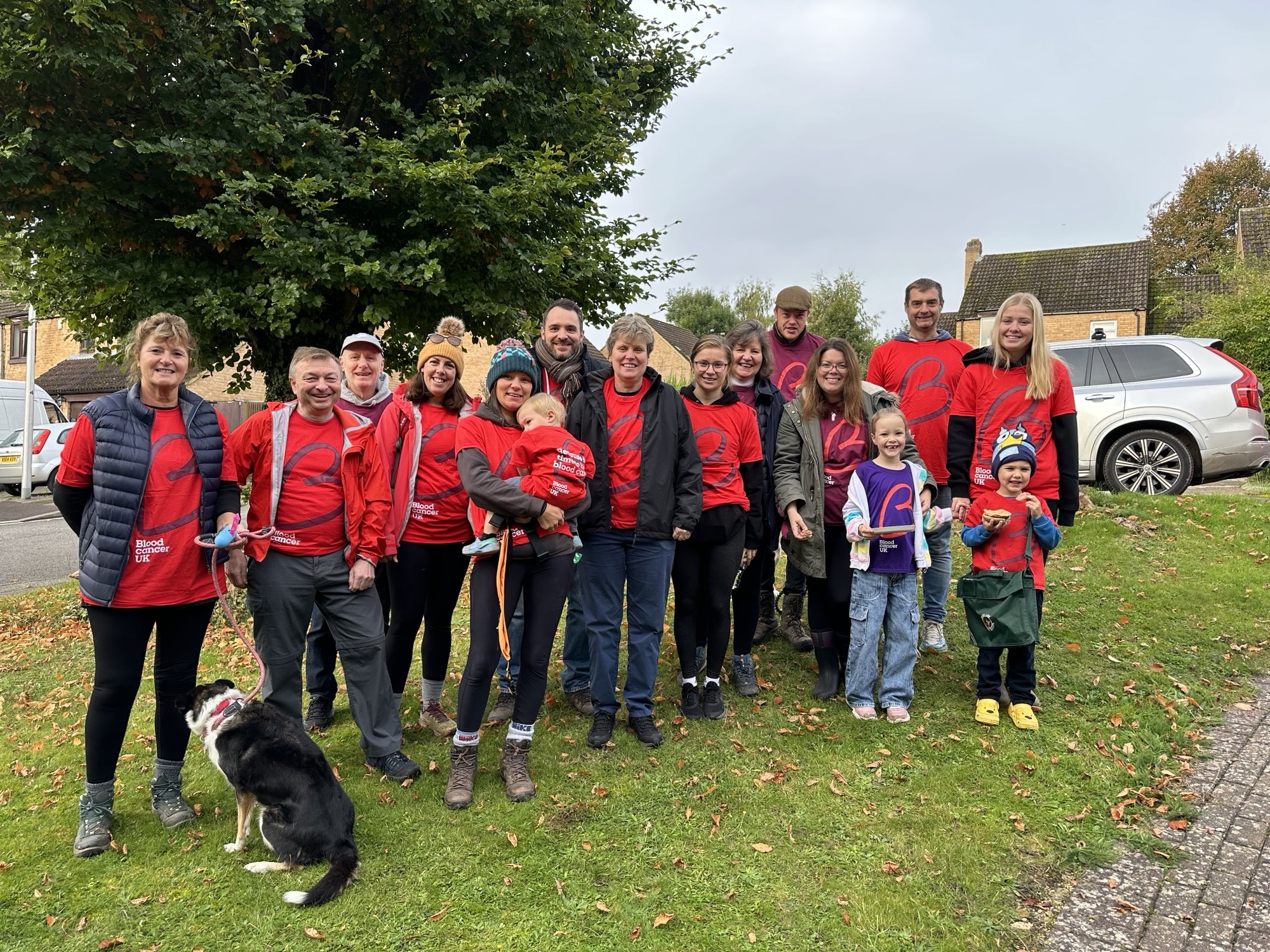 Group of people and pets smiling outside in Blood Cancer UK t-shirts.