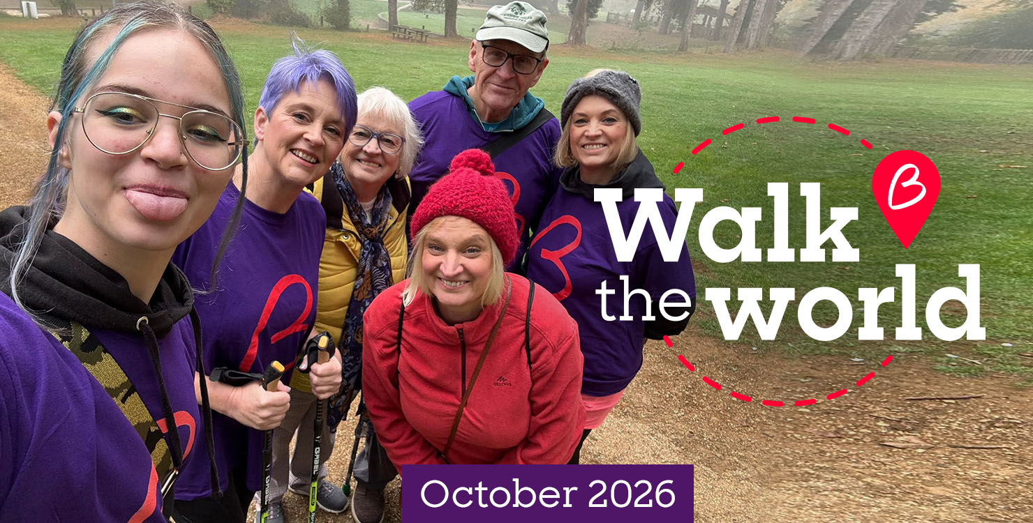 Group of participants posing on a misty park walk, promoting Walk the World in October 2026.