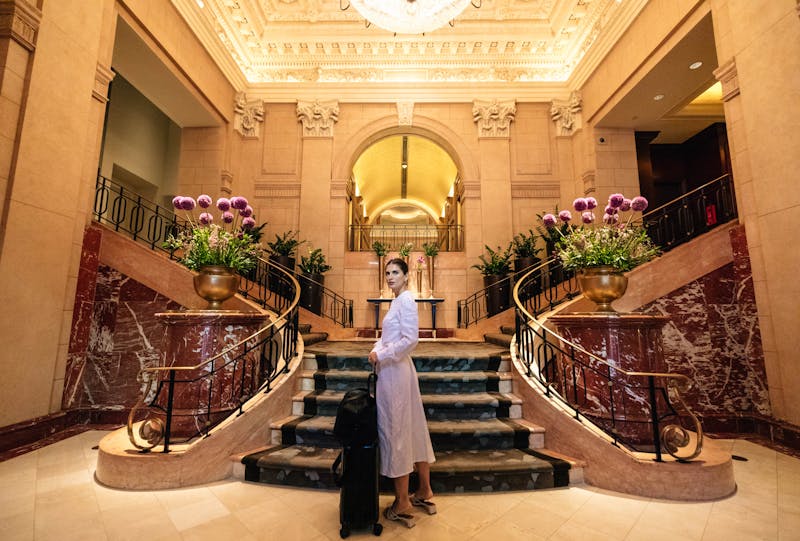 woman standing in front of a hotel lobby's grand staircase