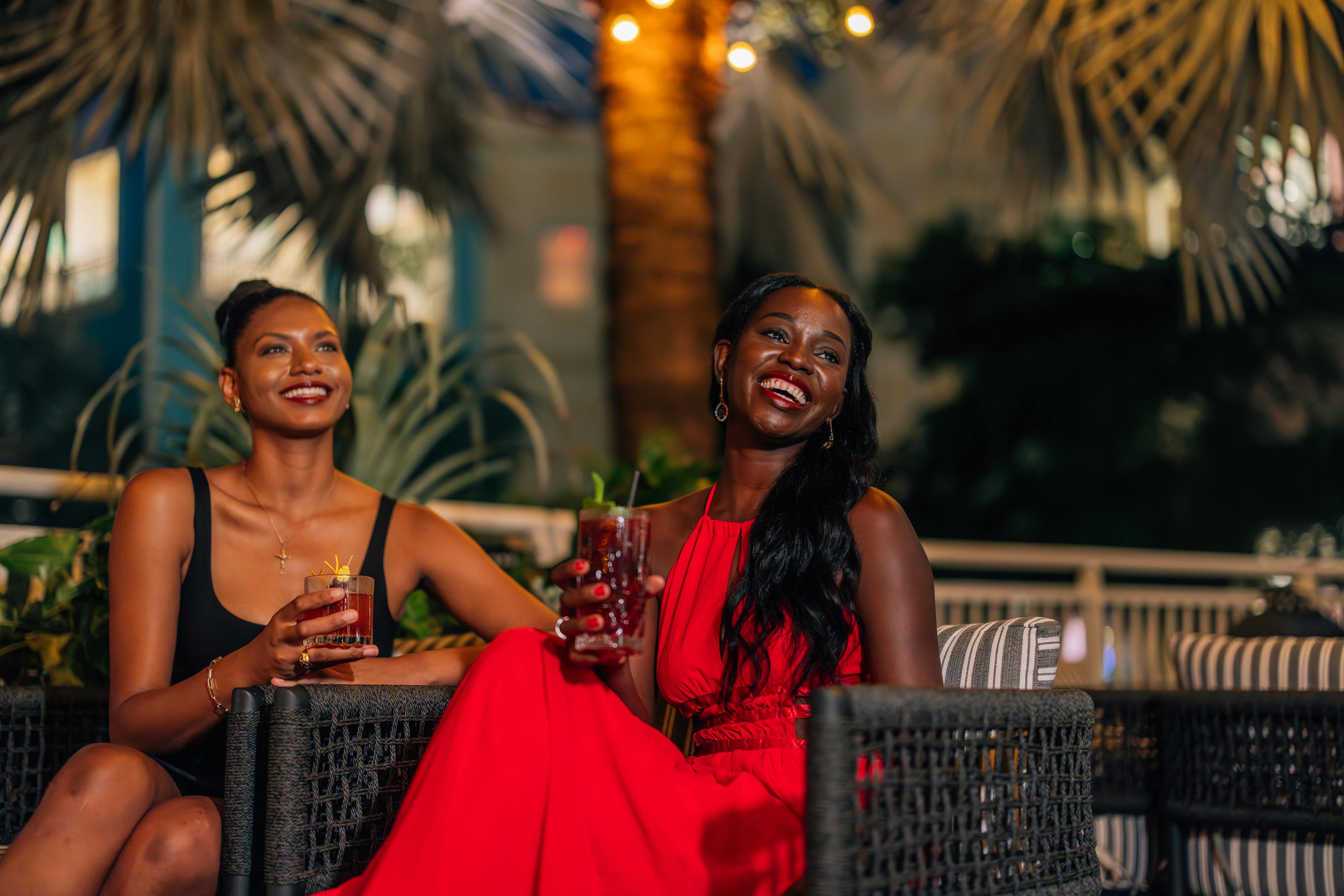 2 women laughing while drinking cocktails
