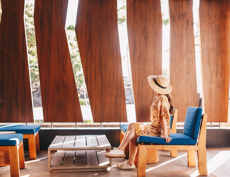 woman in sunhat sitting on a wooden patio