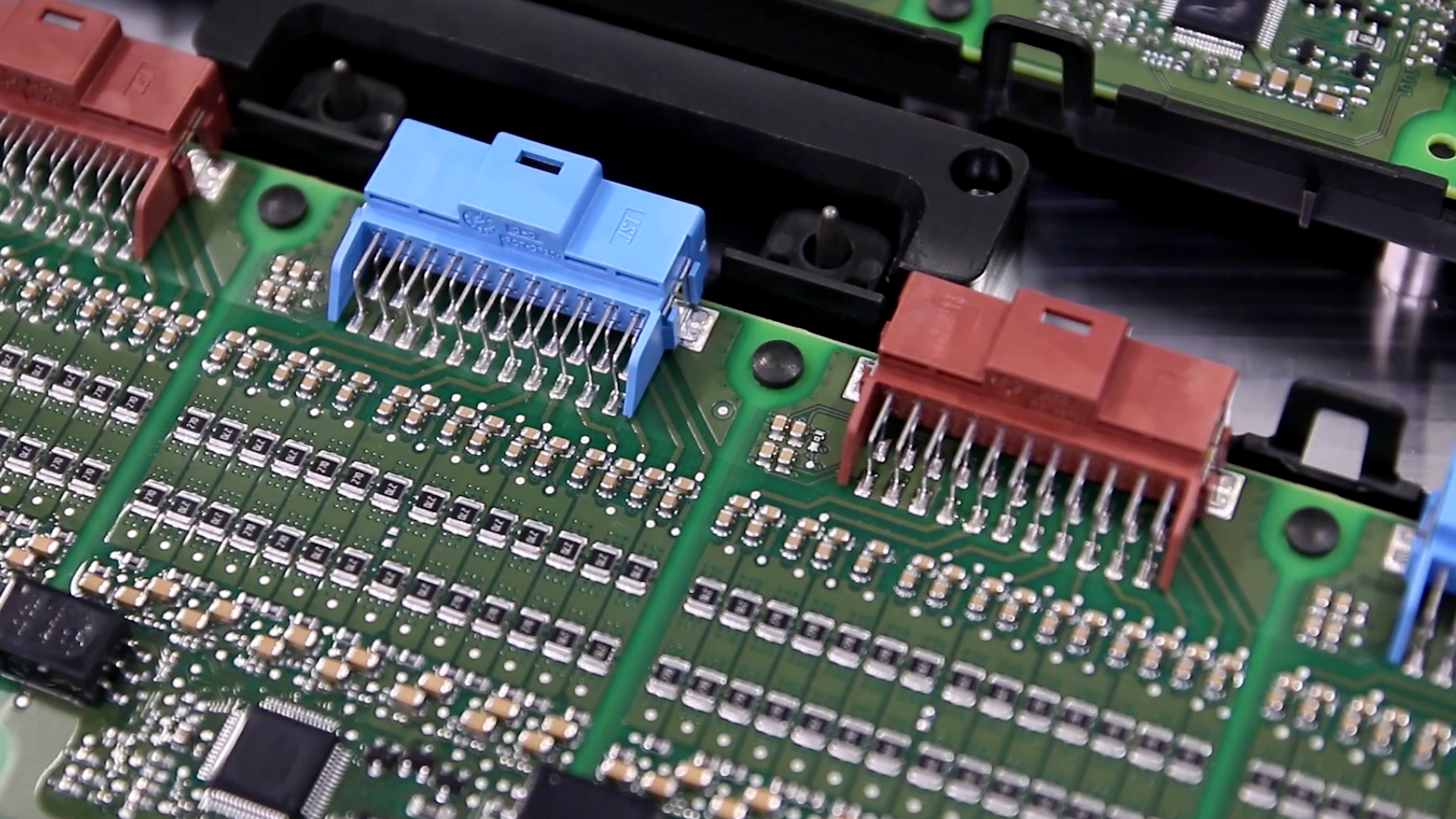 Nahaufnahme einer Elektronik-Platine, die mit einer Heißnietverbindung an einem Bauteil befestigt ist