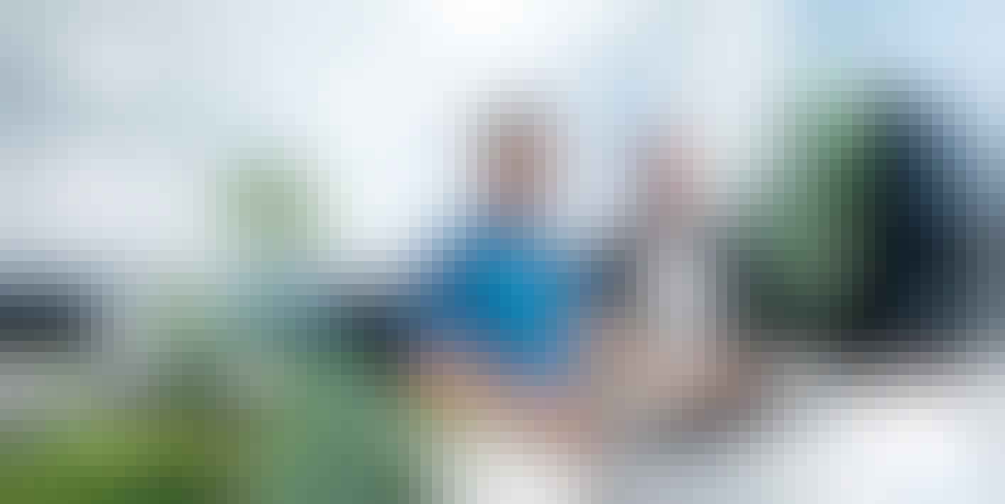 Zwei Mitarbeiter stehen an einem Schreibtisch und blicken auf einen Bildschirm