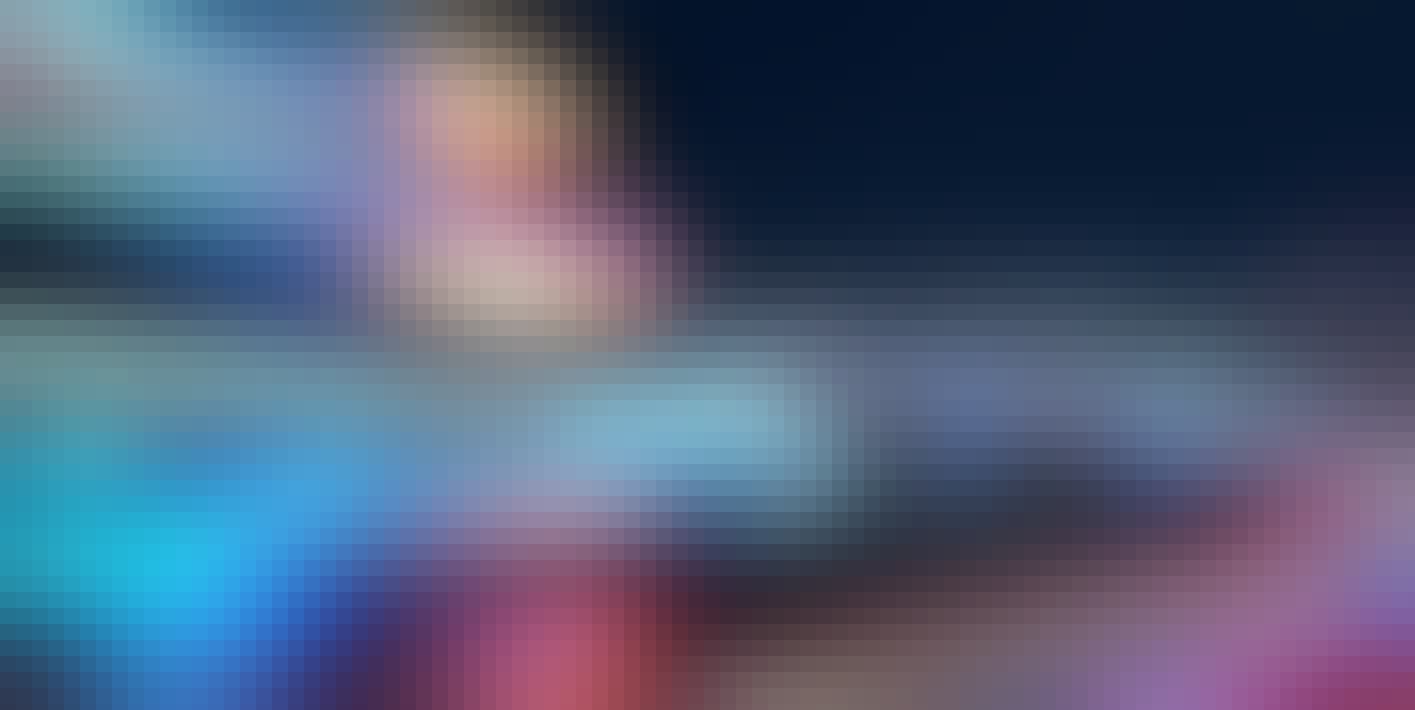 verschiedenfarbige Lichtspuren vor der nächtlichen Skyline einer Stadt