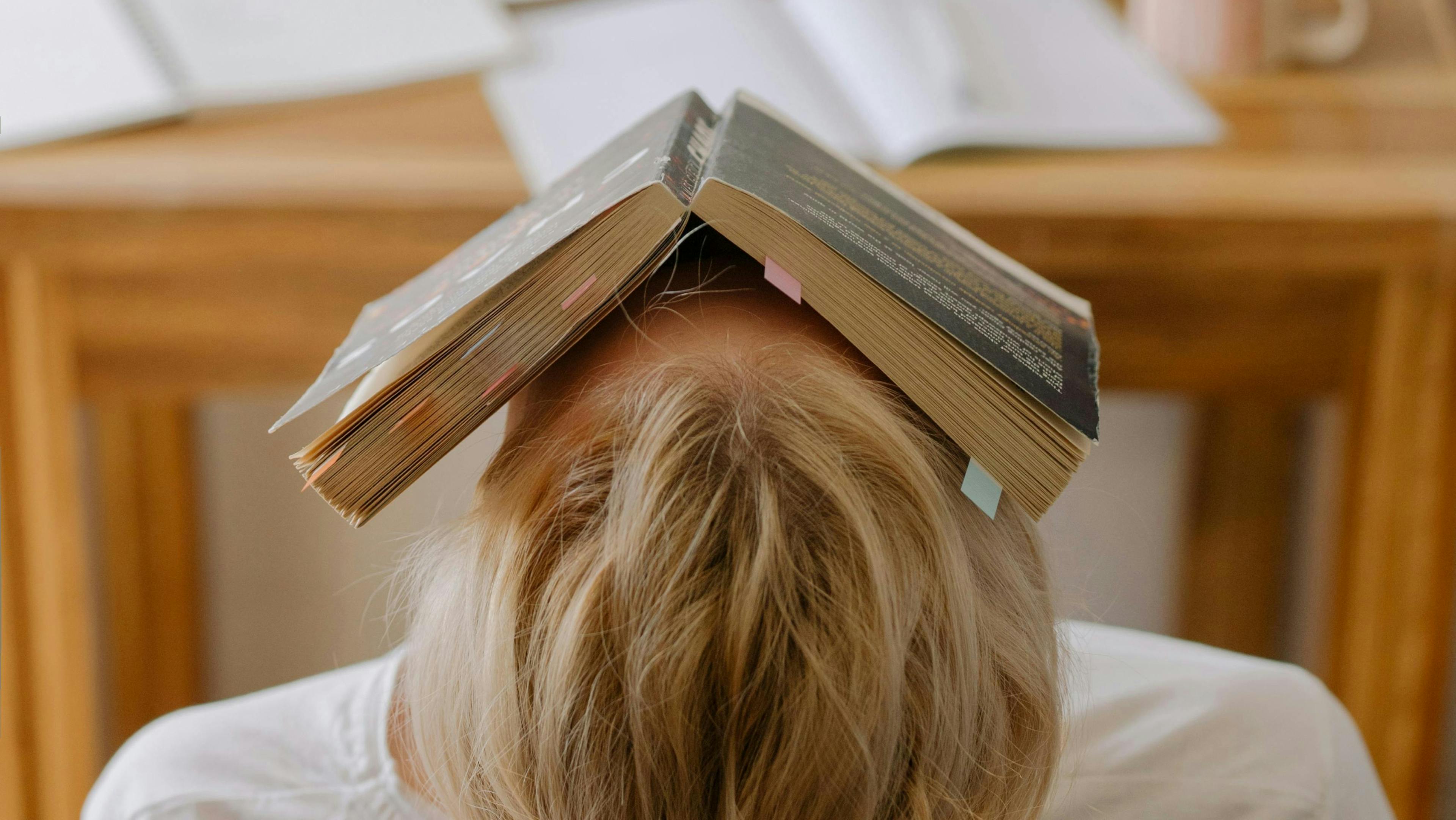 Persona stanca con libro aperto sulla testa