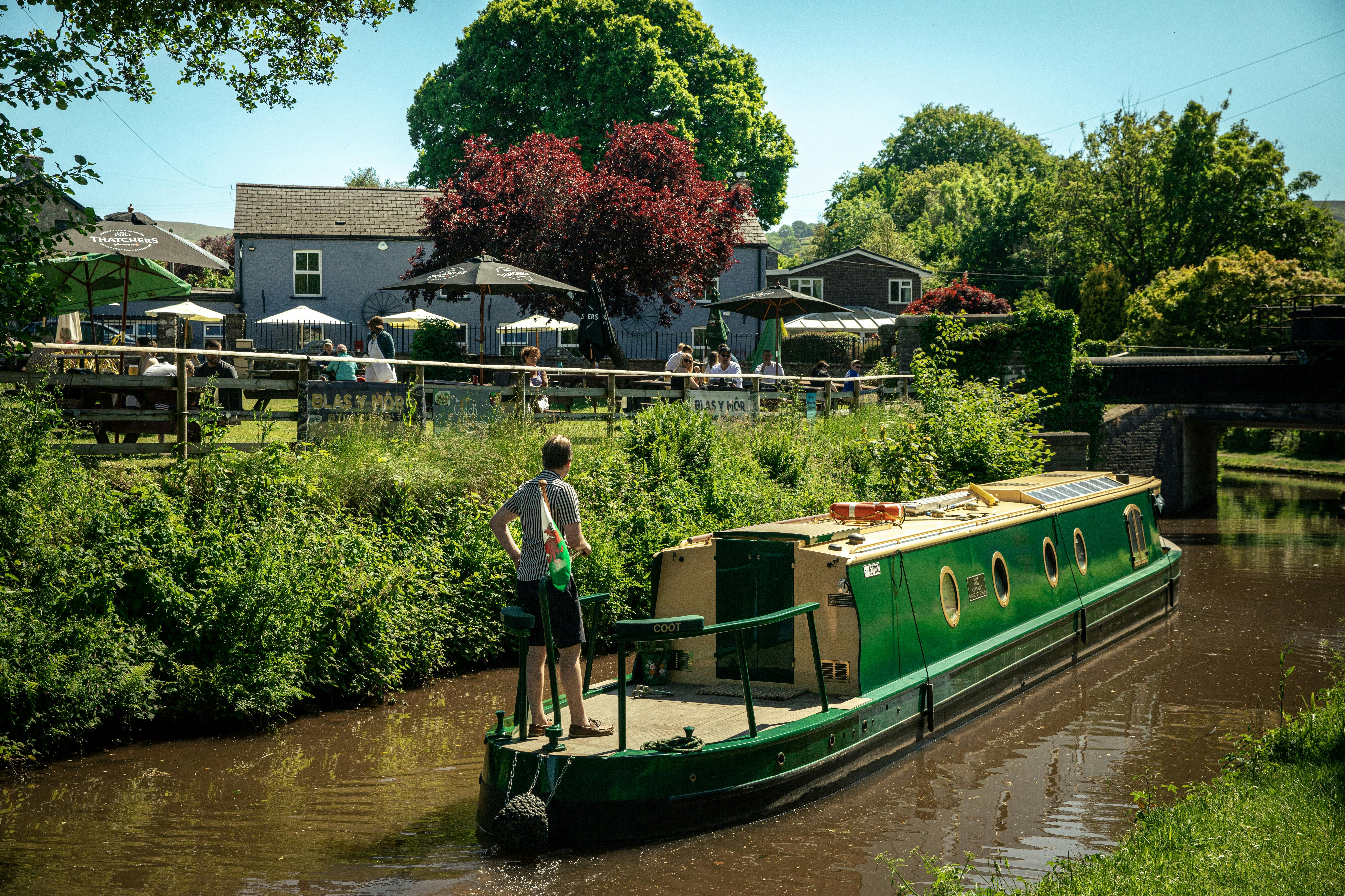 man on a beacon park boat cruising down the mon and brec canal on a sunny day