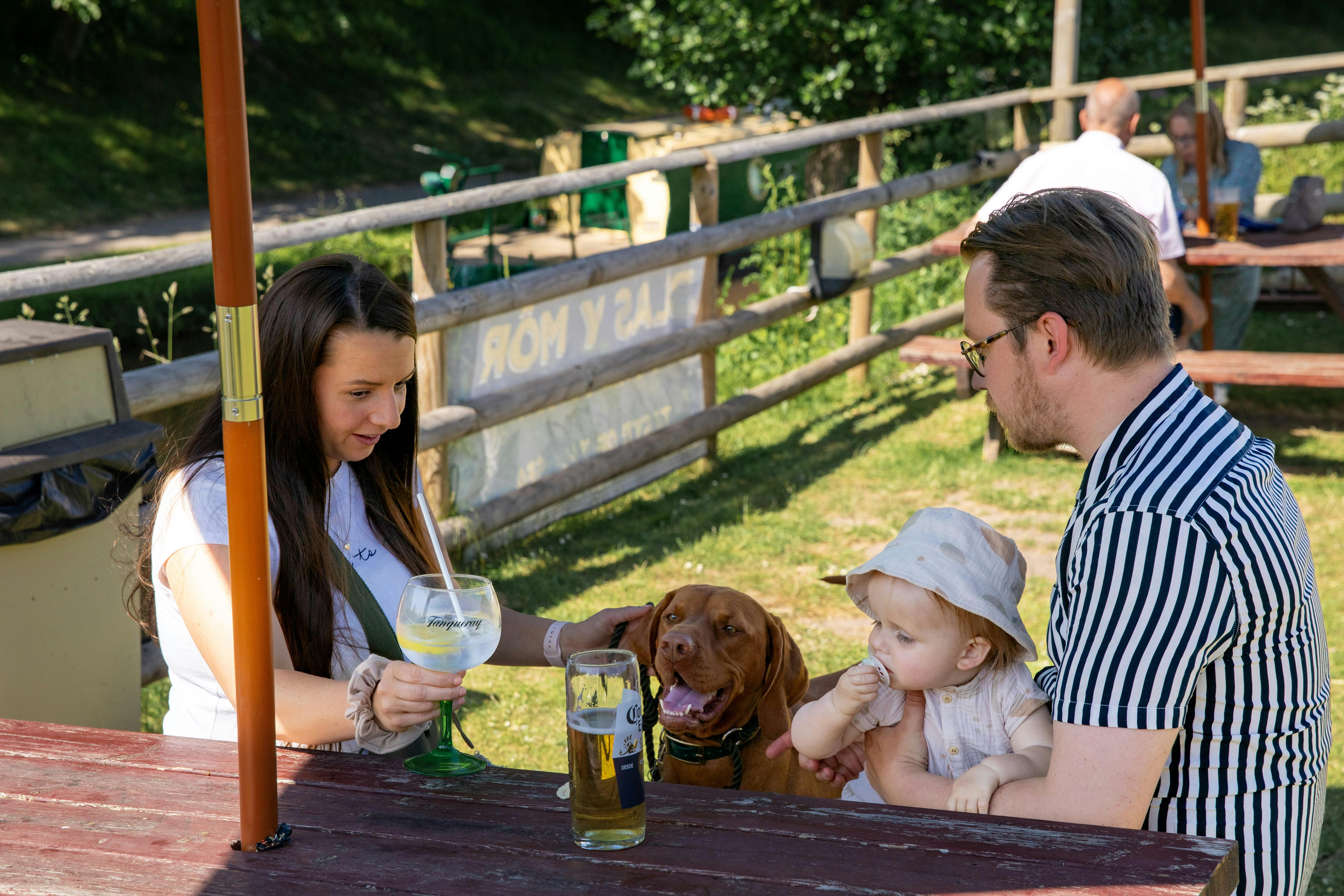 a young family with a dog enjoying a drink in a beer garden on the banks of the mon and brec canal