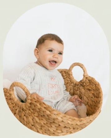 Kinneret sitting in a wick basket smiling